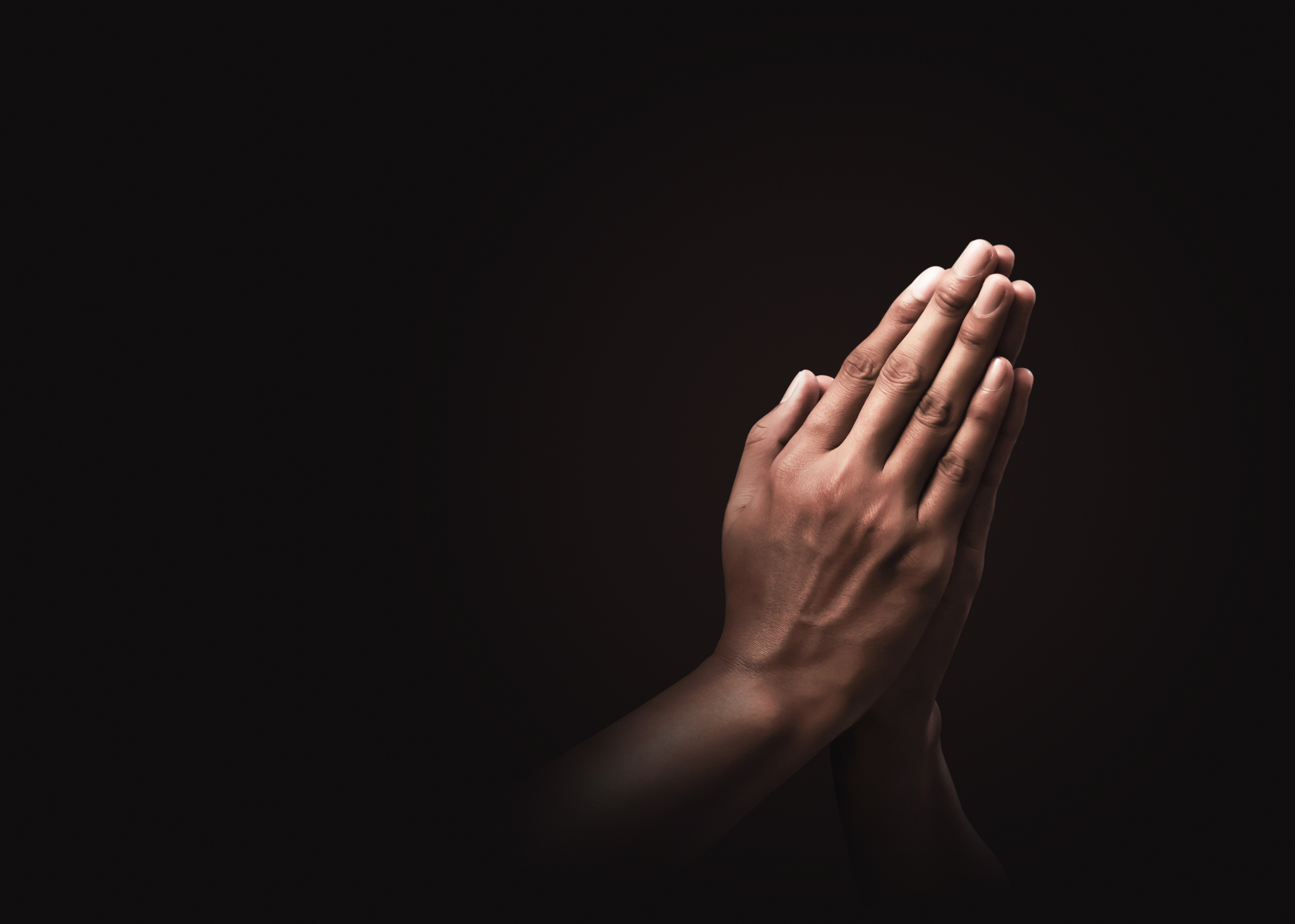Praying hands with faith in religion and belief in God on dark background. 